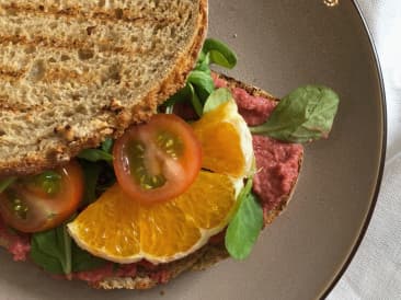 Slice of bread with beet hummus and orange