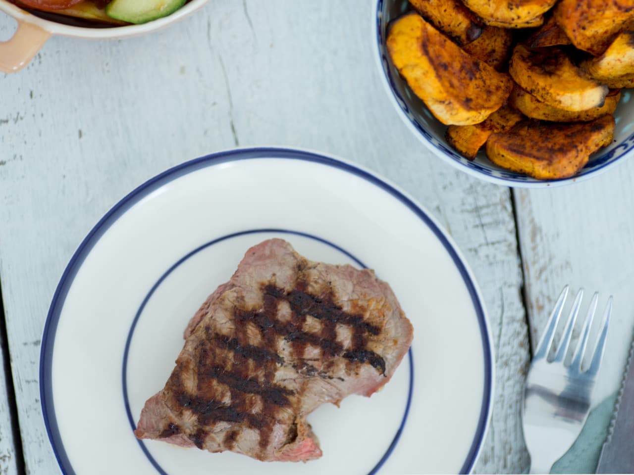 Steak with sweet potato wedges and tomato salad
