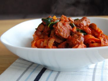 Carrot pasta with bacon, sausage and tomato sauce