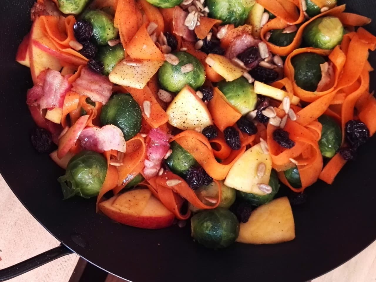 Coles de Bruselas salteadas con tagliatelle de zanahoria y tocino